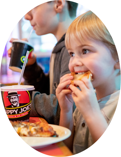 Oval Image of Child Eating a Slice of Happy Joe's Pizza