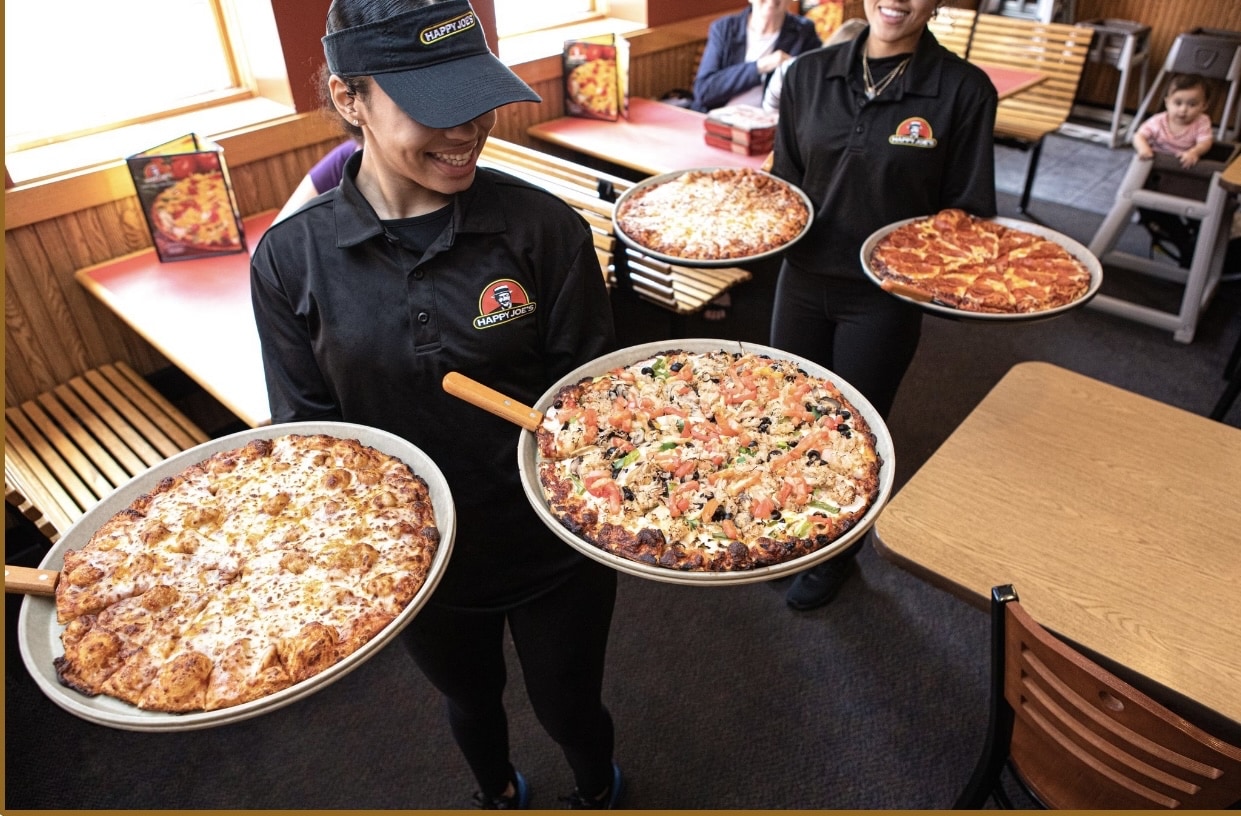 Smiling servers bringing out Happy Joe's Pizzas