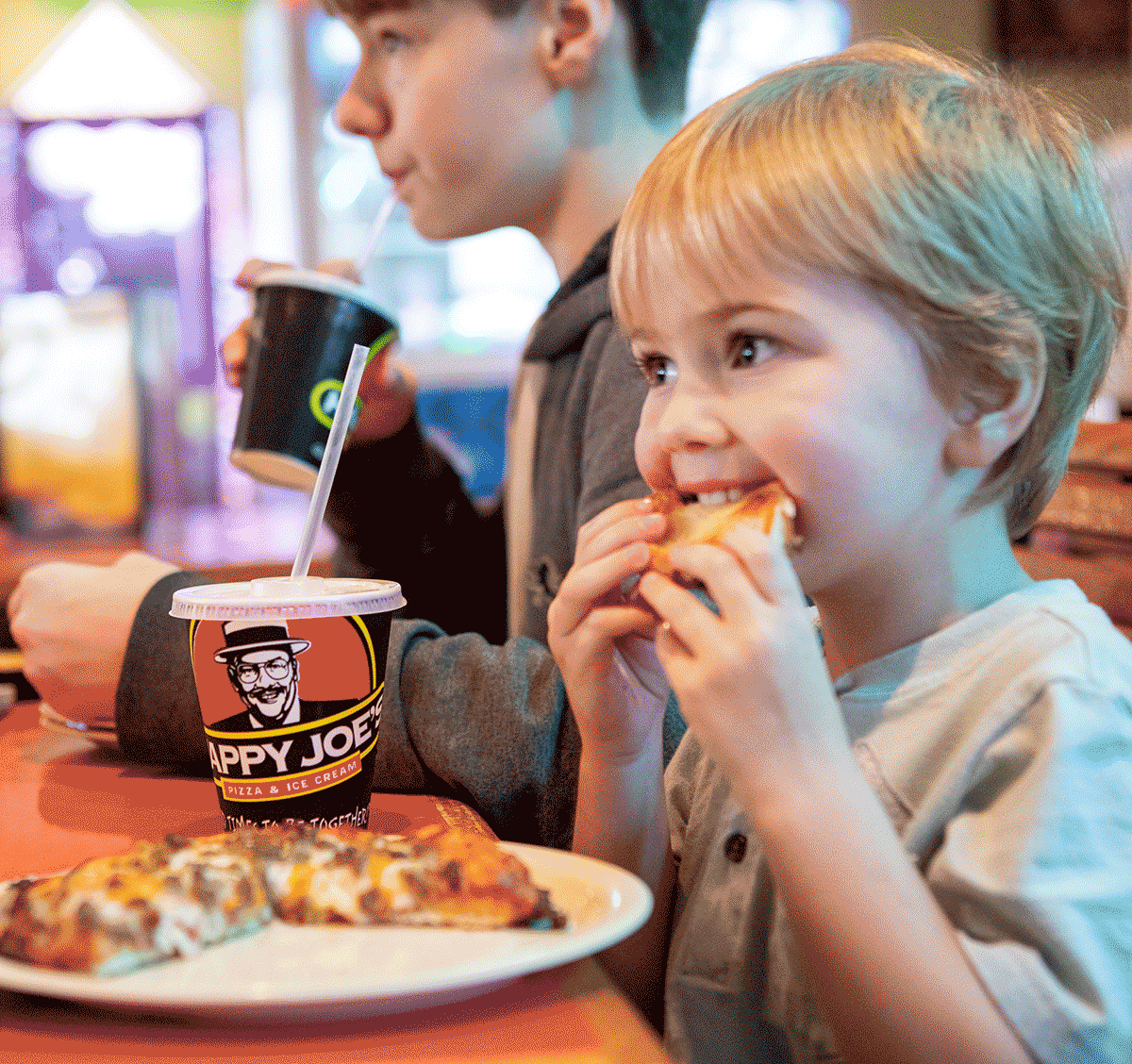 Child eating a slice of pizza at Happy Joe's