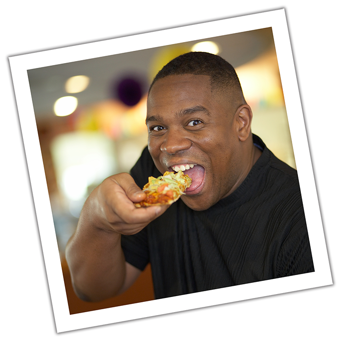 Man enjoying a slice of Taco Pizza from Happy Joe's.