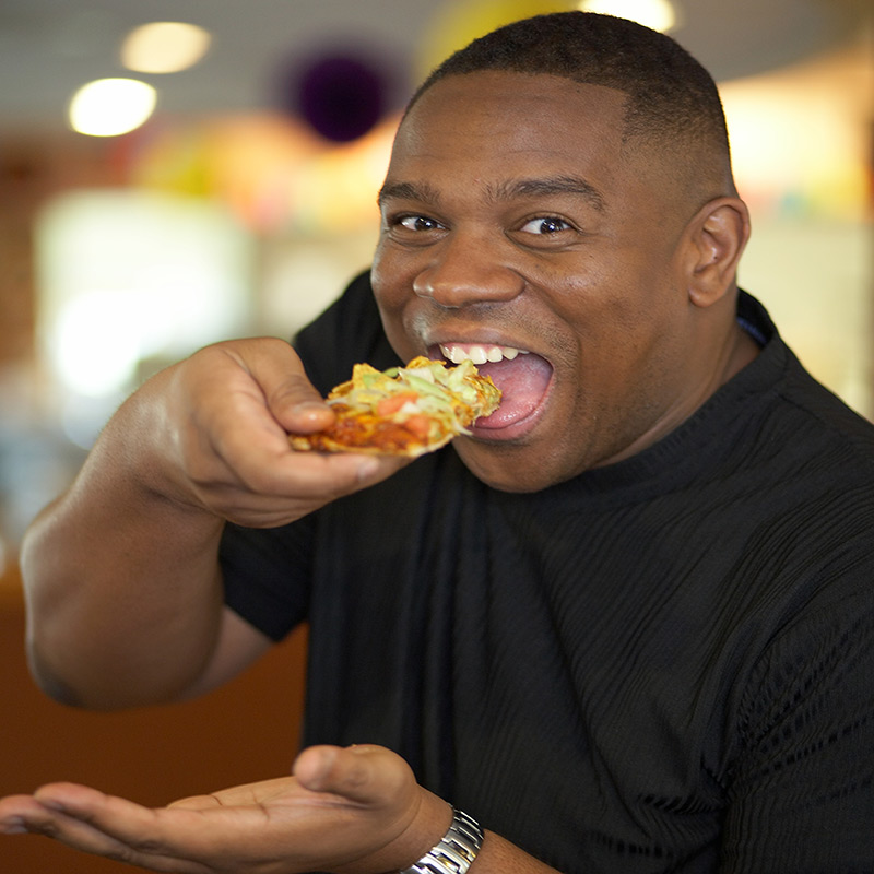 Locust Street - Man enjoying a slice of Happy Joe's Taco Pizza.